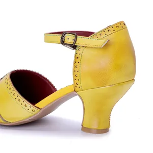 Dettaglio di sandalo vintage in pelle gialla con trafori brogue e cinturino con fibbia.