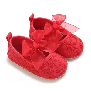 Nahaufnahme von roten Babyschuhen mit großer Schleife und feiner Blumenstickerei