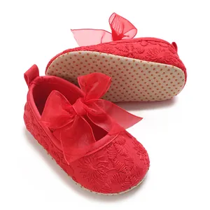 Detailansicht der roten Babyschuhe mit Blumenstickerei und großer Organzaschleife