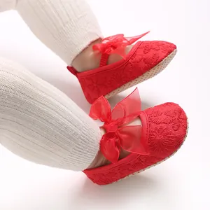 Nahaufnahme rote Babyschuhe mit großer Schleife und filigraner Stickerei für Mädchen