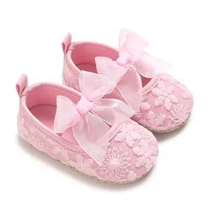 Nahaufnahme von rosa Babyschuhen für Mädchen mit floraler Spitze und Organza-Schleifen.