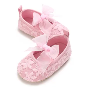Detailansicht von rosa Spitzen-Babyschuhen für Mädchen mit einer großen Organzaschleife