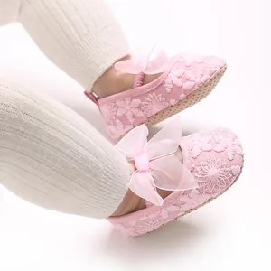 Detailansicht von rosa Lauflernschuhen für Babys mit Blumenstickerei und Organzaschleifen