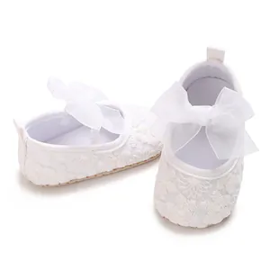 Detaillierte Ansicht eleganter weißer Babyschuhe aus Spitze mit einer großen Schleife