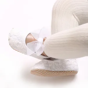 Detailansicht eleganter Lauflernschuhe für Babys aus weißer Spitze mit großer Organzaschleife.