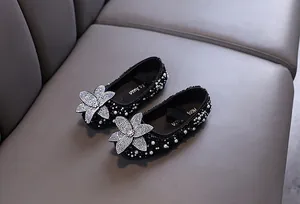 Close-up view of black girl's princess flats featuring rhinestone flower and pearls