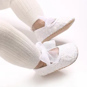 Nahaufnahme weißer Baby-Lauflernschuhe aus Spitze mit eleganter Schleifendekoration