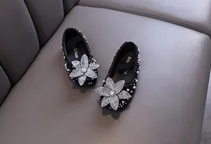 Top view of girls black rhinestone flower princess flat shoes on leather background