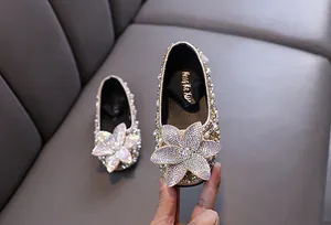 Close-up detail of girls' sparkly princess shoes with large rhinestone flower decoration.