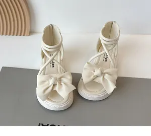 Gros plan détaillé de sandales romaines blanc crème pour filles avec un nœud de mode