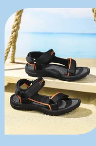 Primer plano de sandalias deportivas negras y naranjas para niños en una playa soleada