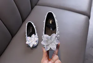 Close-up of girls' silver rhinestone princess shoes with elegant floral crystal deco