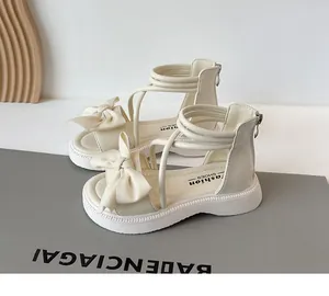 Vue détaillée de sandales romaines pour filles en crème avec nœud et semelle souple.