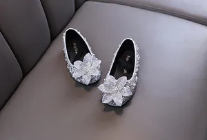 Detailed view of silver girl princess shoes with sparkling rhinestones and large flower decor.