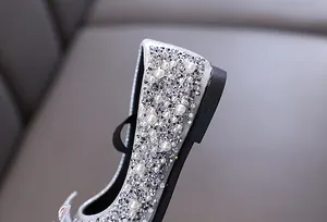 Macro detail of sparkly silver girl's princess shoes with pearls and rhinestones