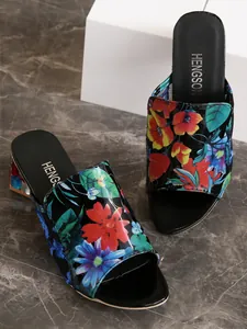 Vista detallada del patrón floral y la textura de charol en sandalias mules con tacón