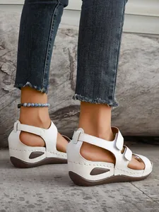 Side view of white women's wedge peep-toe sandals with adjustable velcro straps on model