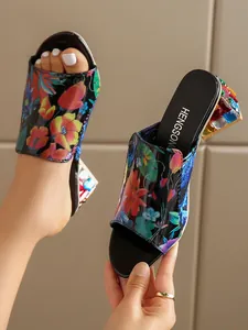 Detalle de sandalias de flores para mujer con tacón de bloque con piedras de colores.