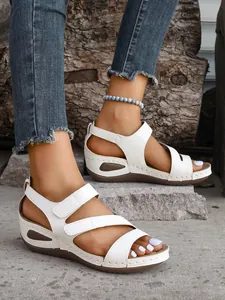 Detail view of white wedge open-toe sandals with adjustable Velcro straps