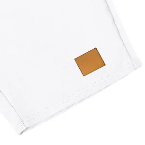 Primo piano dei dettagli di pantaloncini in lino bianco con cuciture e toppa in pelle.