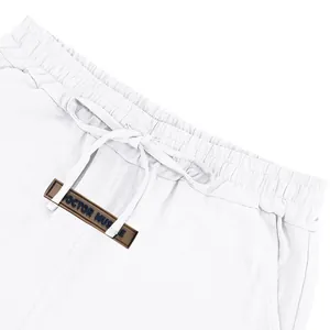 Close-up detail of white linen shorts waistband with drawstring and branded patch