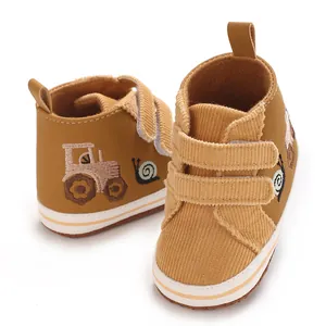 Primer plano de zapatos marrones para bebé con textura de pana y bordado de un tractor infantil