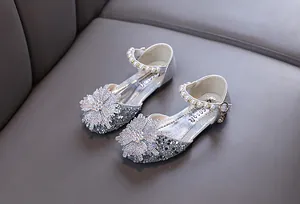 Close-up of silver glitter princess shoes with rhinestone flowers and pearl straps