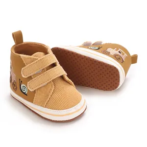 Vista detallada de zapatos para bebé con textura de pana y diseño bordado de tractor