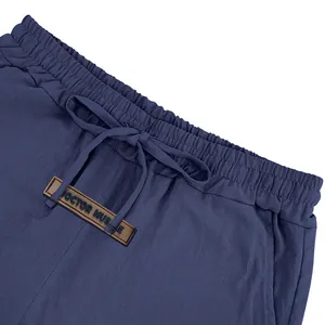 Close-up of elastic waistband with drawstring and 'DOCTOR MUSCLE' patch on linen shorts