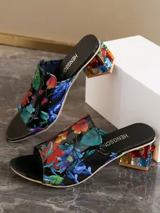 Detalle de sandalias tipo mula con estampado floral y tacones joya de pedrería de colores.