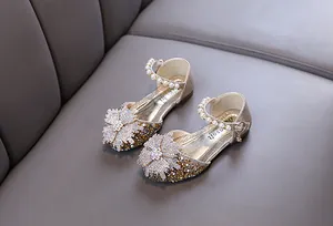 Detailed view of champagne gold princess shoes with rhinestone flowers and pearls