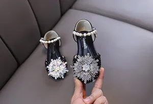Detail of girls' black princess shoes with rhinestone snowflake and pearl strap