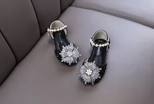 Detailed view of girls' black glitter dress shoes with rhinestone snowflake and pearl strap