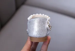 Close-up of silver glitter princess shoes for girls with elegant pearl strap