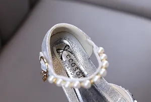 Macro view of silver glitter girl princess shoes with elegant pearl strap detailing.