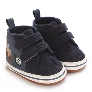 Detalle de zapatos azul marino para bebé con bordado de caracol y velcro.