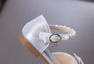 Close-up detail of silver glitter girl's princess shoe with pearl strap and star charm