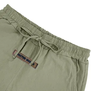 Close-up of army green breathable men's linen shorts with drawstring waist and logo.