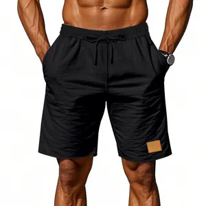Dettaglio pantaloncini estivi da uomo in lino nero con coulisse in vita e toppa decorativa.