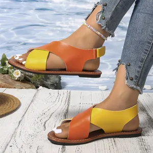 Vista detallada de las sandalias romanas planas de mujer con correas cruzadas naranja y amarillo.