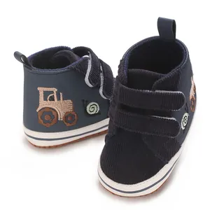 Primer plano de los zapatos de bebé azul marino con bordado de tractor y cierre velcro