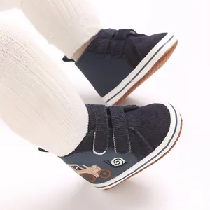 Primer plano de zapatos para bebé azul marino con bordado de tractor y velcro