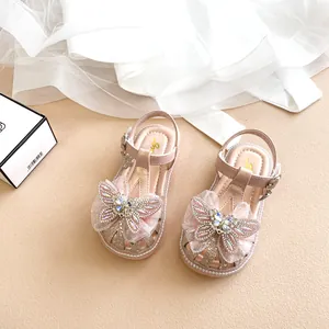Detailaufnahme von eleganten rosa Mädchensandalen mit glitzerndem Kristallschmetterling
