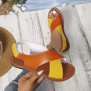 Detalle de las sandalias planas para mujer con correas cruzadas en naranja y amarillo.