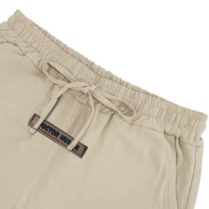 Close-up detail of khaki men's linen shorts waistband with drawstring and brand label