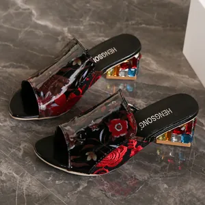 Vista detallada de mulas bordadas con flores y tacones anchos con joyas de colores