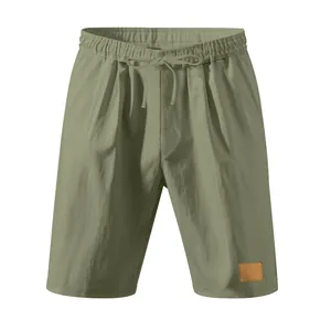 Dettaglio dei pantaloncini in lino verde oliva con vita elastica e toppa in pelle decorativa