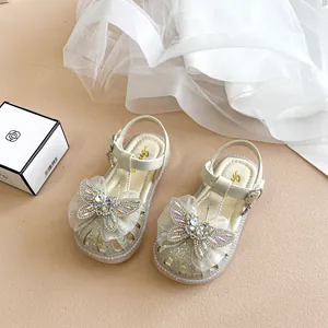Nahaufnahme von glitzernden Mädchensandalen mit großer Netzschleife und Strass