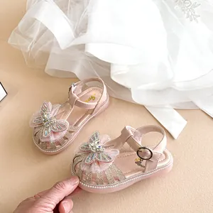 Nahaufnahme rosa Sandalen für Kleinkinder mit Strass-Schleife und Glitzer-Finish.