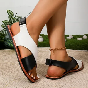 Primer plano de sandalias planas de mujer con tiras cruzadas en blanco y negro